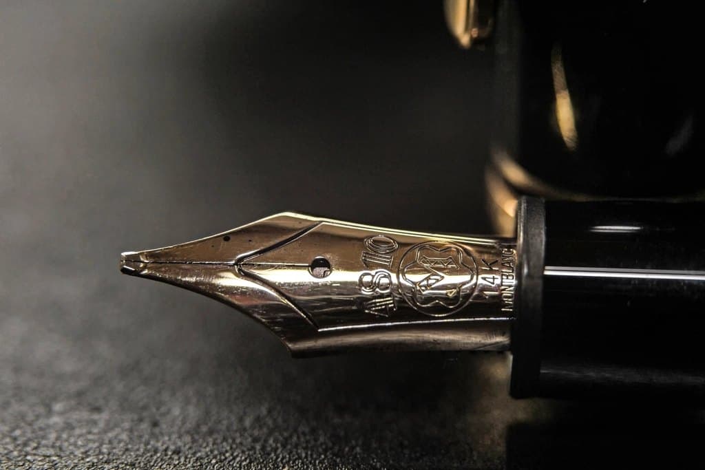 Close-up of a gold fine fountain-pen nib on a dark resin barrel