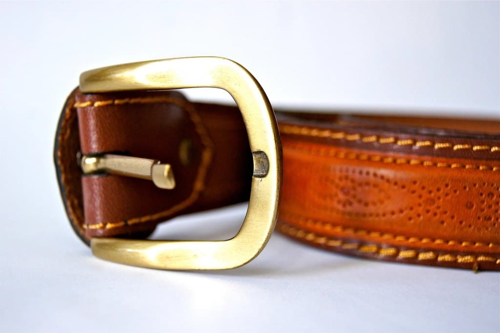 Tan leather belt with a solid brass buckle and saddle stitching