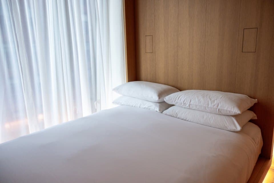 Crisp white duvet and stacked pillows on a sunlit contemporary bed