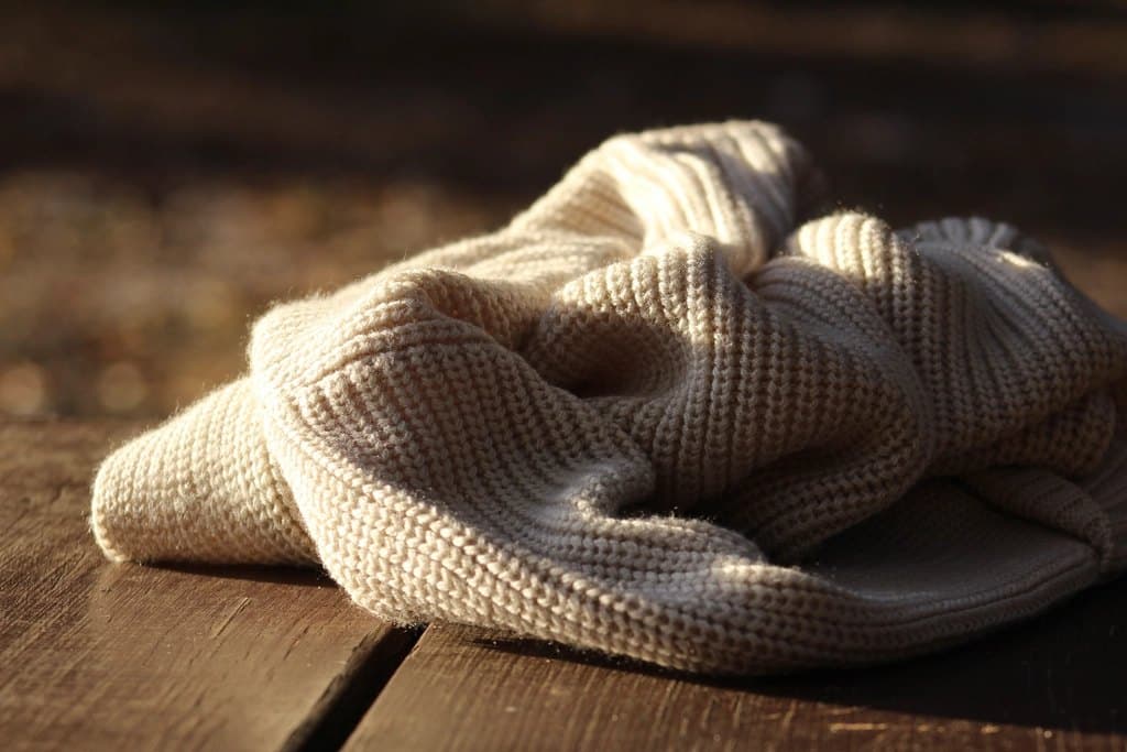 Chunky knit throw blanket folded on a sofa in warm ivory