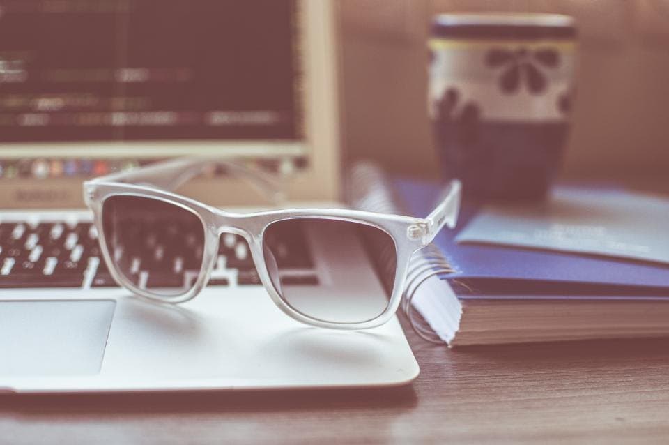 Clear acetate sunglasses with dark lenses resting on a laptop keyboard