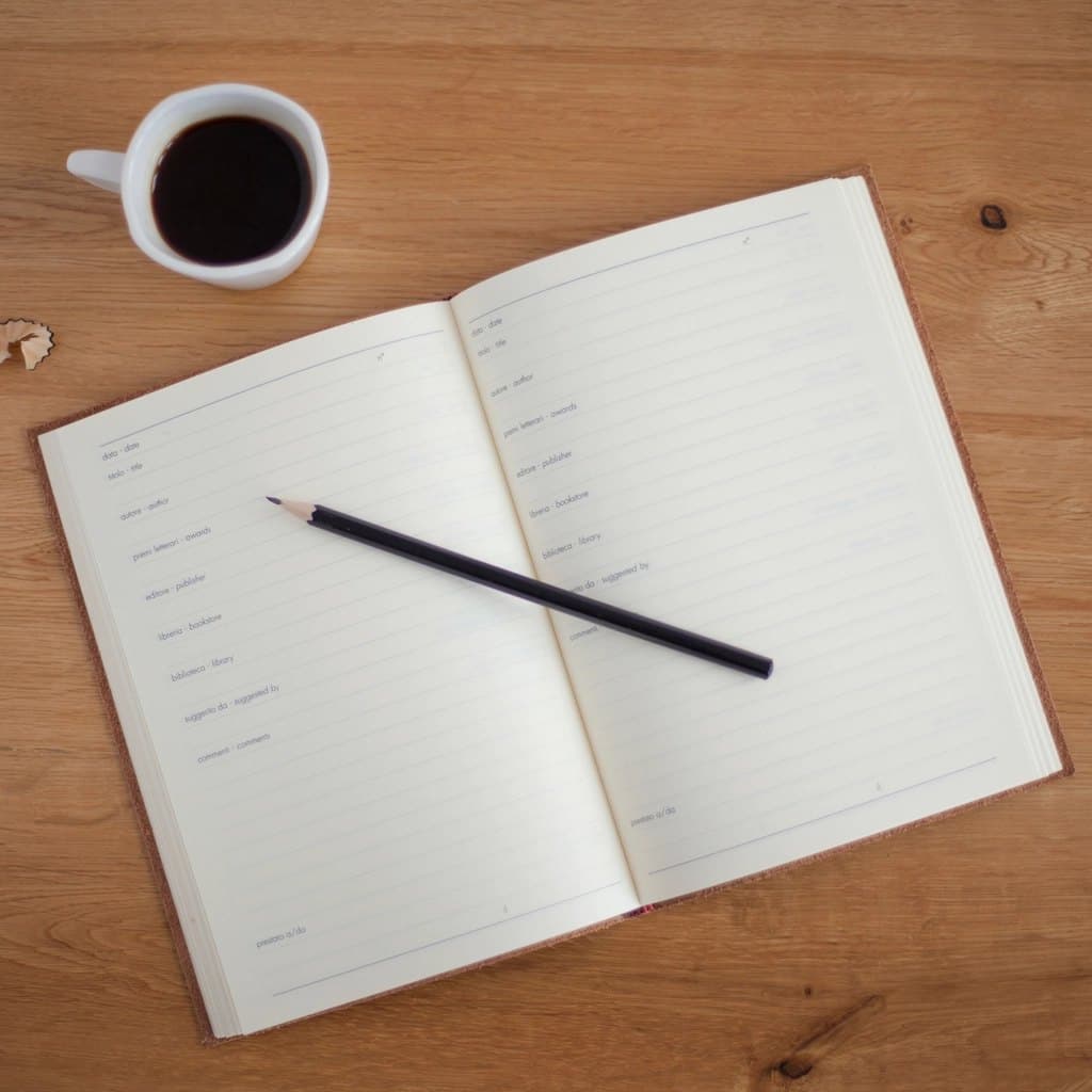 Open reading-log journal with bilingual fields, a pencil, and a cup of coffee
