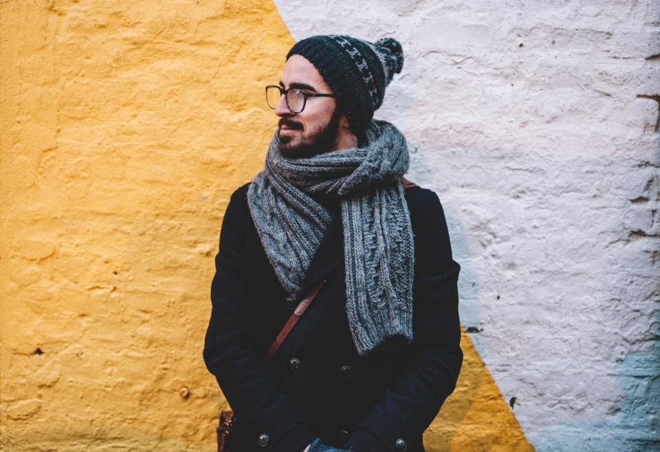 Grey cable-knit wool scarf worn with a dark coat and knit beanie
